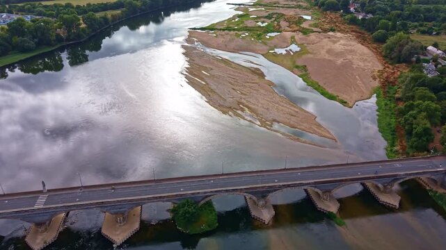 Pont Dumnacus crosses the Loire at Les Ponts de Ce, Maine et Loire, with exposed alluvial bars, shallow channels and broad low flow areas revealing the riverbed, Pays de la Loire France drone pull out