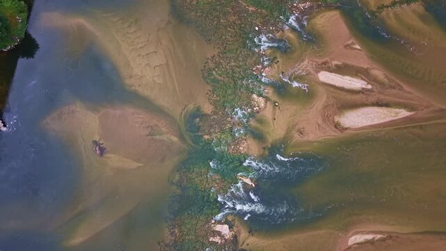 Loire River at very low water reveals branching shallow channels, elongated alluvial bars, fine sediment deposits and vegetated mid-channel features across an exposed braided riverbed, France, aerial