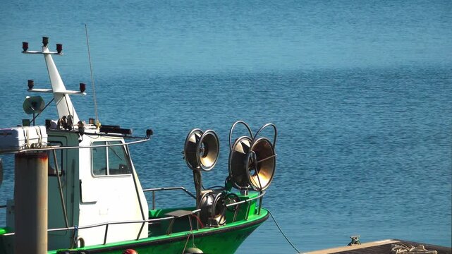 coastal fishing boat with net reels moored next to a wooden dock