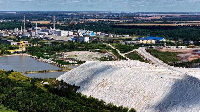 Wide aerial view of industrial plant and large white phosphogypsum stack near water