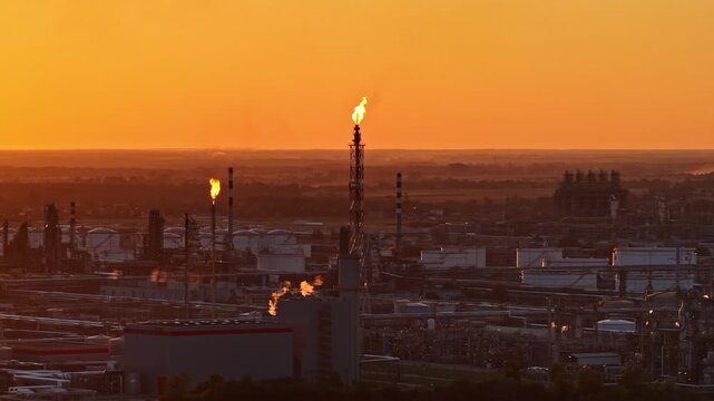 Orlen oil refinery in Płock, Poland, with flare stacks burning excess gas at sunset
