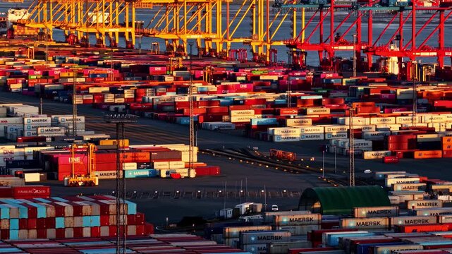 Colorful shipping containers and gantry cranes in the busy port of Bremerhaven, Germany in aerial time lapse during sunset
