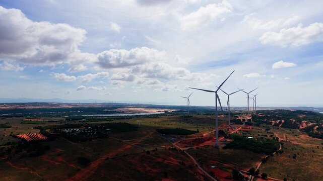Wind turbines rotate in Hoa Thang, Lam Dong. The sun shines brightly in the sky. Green fields stretch out beneath the turbines. This area is ideal for enjoying nature and exploration.