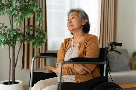 Thoughtful senior woman seated in a wheelchair at home, gazing toward a window in natural light, representing aging, mobility challenges, elderly wellbeing, independence and long term care.