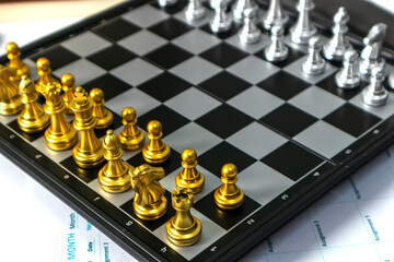 Gold knight and rook chess pieces on a board, representing teamwork, strategic roles, and business competition. © oselote