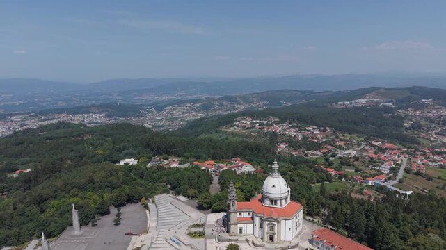 Aerial - Sameiro Sanctuary with its white dome and esplanade above villages and hills near Braga