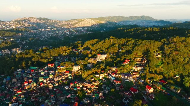 Rising aerial turn reveals Baguio homes, pine forests and mountains at sunrise