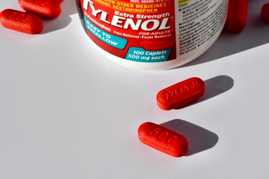 Tylenol bottle with red pills on a white background