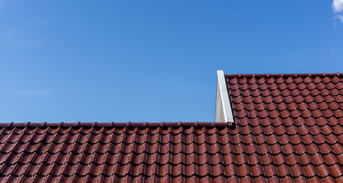 House roof with terracotta tiles against blue sky