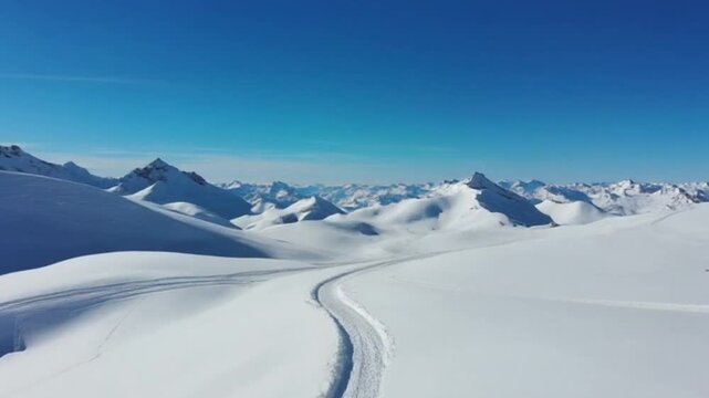 Snowy mountain landscape with ski tracks under a clear blue sky in winter