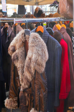 Vintage winter coats and fur jacket hanging on rack at outdoor street flea market