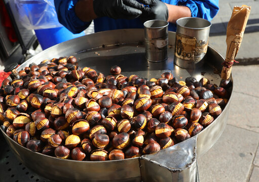 Freshly roasted chestnuts cooked on a street food cart pan in Milan Italy