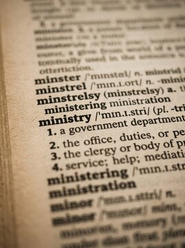 Close-up of the word Ministry and its definition in an old vintage dictionary book page with shallow depth of field