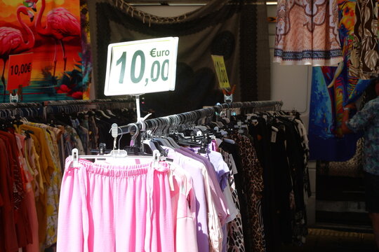 Rack of colorful clothes with ten euro price sign at local street market