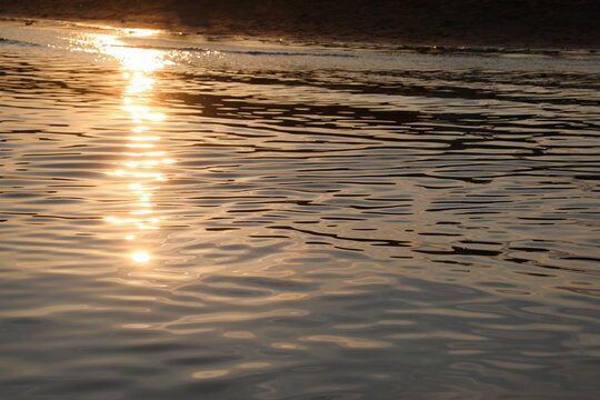 Golden sunset reflection on calm sea water surface ripples