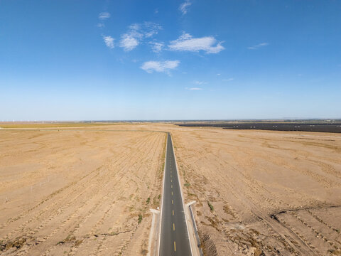 straight road extending into the distance across vast desert wilderness under blue sky