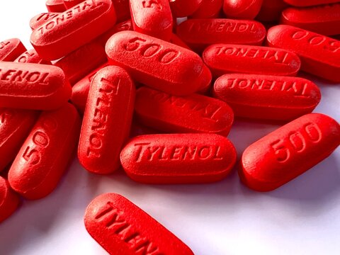 red extra strength Tylenol pills on a white background