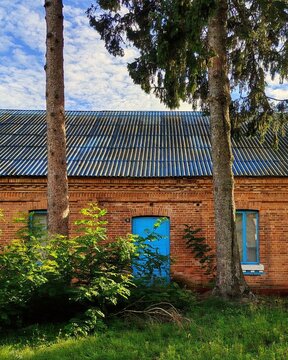 Vertical shot of a red brick house facade with bright blue wooden door and scenic cloudy sky