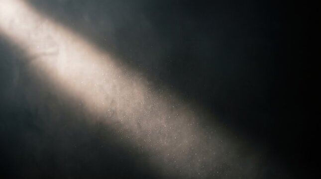 A diagonal beam of light cutting through dusty air against a dark background