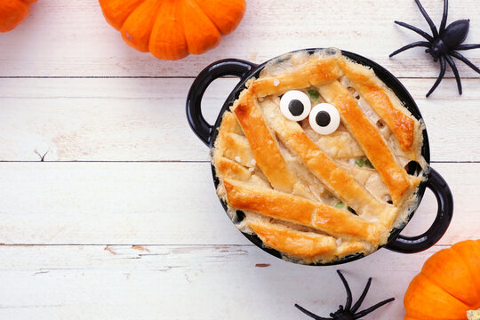 Halloween mummy chicken pot pie. Top view table scene on a white wood background. Copy space.