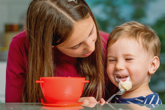 Little brother being fed by his caring older sister.