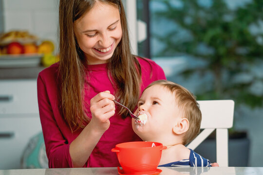 Teenage sister feeding her young brother healthy homemade food.