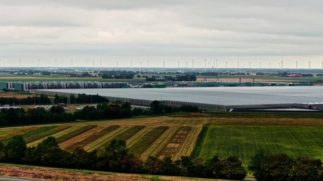 Aerial view of the large-scale Agriport A7 greenhouse complex surrounded by agricultural fields and wind turbines in Middenmeer, Noord-Holland, Netherlands.