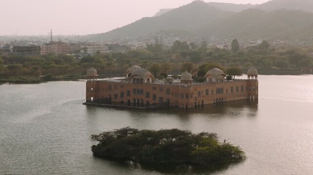 Aerial view of jal mahal palace floating on man sagar lake in jaipur, india, with the city and aravalli hills in the background