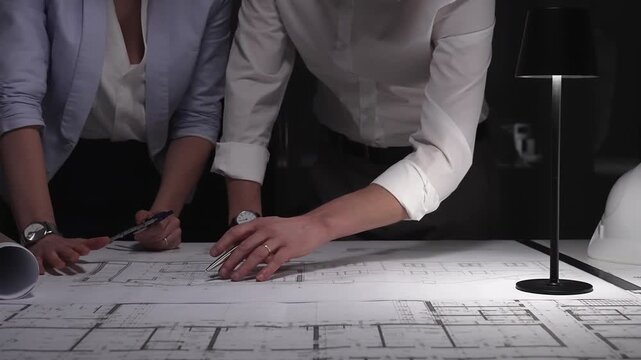 Architects and engineers collaborating on blueprint plans, working together on an architecture project layout design late at night.