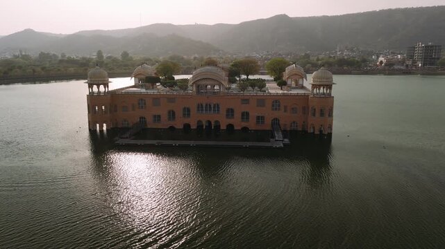 Jal mahal water palace aerial view with sun glare on man sagar lake in jaipur, india, revealing the city and mountains