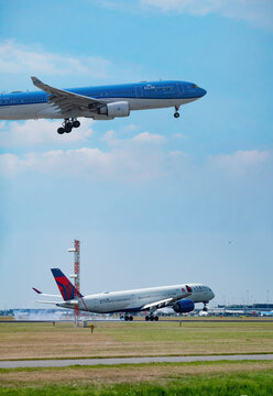 July 30, 2026. Netherlands, Amsterdam. KLM Aircraft Flying Above Delta Plane Landing at Amsterdam Schiphol Airport