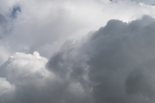Storm cloud gathering. Dark storm cloud building rapidly. Eminent thunderhead with fierce swirling formations. Overhanging storm cloud with turbulent structures and heavy moisture