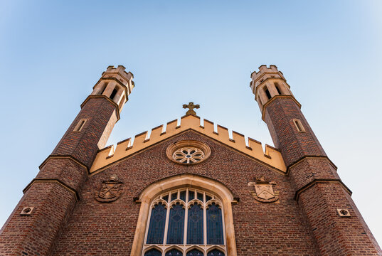Historic red brick church with twin towers viewed from below