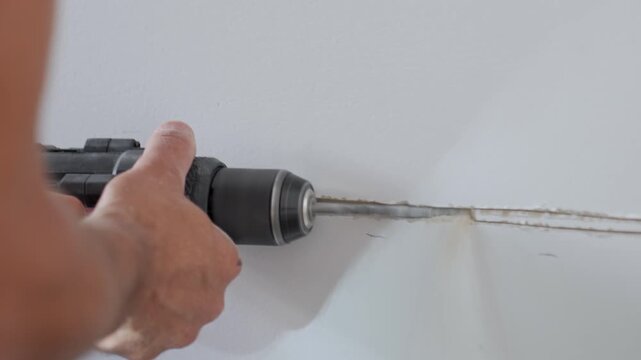 Man using power tool to cut horizontal channel in interior wall. Preparing wall for electrical wiring during home renovation