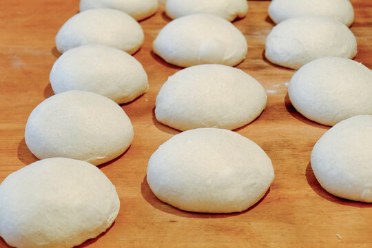 Rows of fresh dough balls on a wooden board