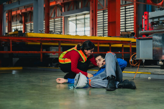 Concerned workers employed in industrial plants specifically in metal sheet industry and other industrial facilities help an injured colleague