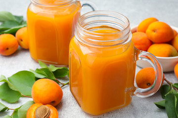 Apricot juice in mason jars, fresh fruits and leaves on light table, closeup © New Africa