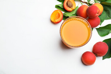 Glass of apricot juice, fresh fruits and leaves on white table, flat lay. Space for text © New Africa