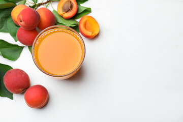 Glass of apricot juice, fresh fruits and leaves on white table, flat lay. Space for text © New Africa