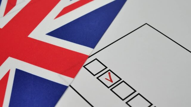 Voter ticks the box next to their candidate on the paper ballot with a red marker. Democratic elections in the UK. The flag of the United Kingdom on the background