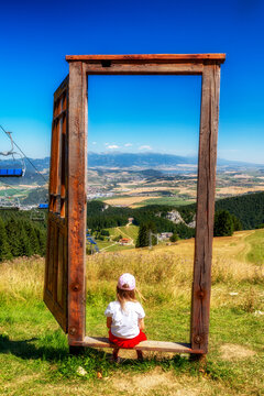 Child sitting in wooden frame on Malinne summit overlooking Liptov and Tatra Mountains in Slovakia