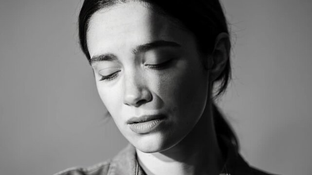 Shifting studio light causing woman turning head at studio, seeming sad with collared shirt