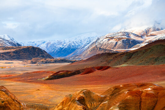 Red colorful mountains in Kyzyl-Chin valley in Altai, Siberia, Russia. Snow-covered mountains in the background.