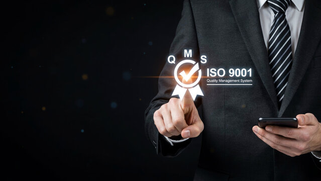 Businessman touching an ISO 9001 quality management system certification icon on a digital screen.