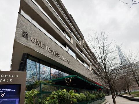 One Tower Bridge modern building with The Ivy restaurant frontage in London, UK showing urban architecture, terrace dining and Shard skyline on an overcast day