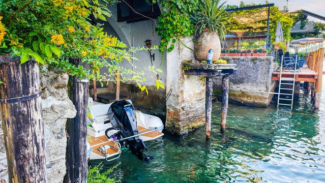Traditional Italian lakeside atmosphere with a motorboat stored in a waterside boathouse garage, capturing the charm of lakefront living and boating on the Italian Lakes district