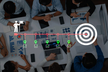 A diverse team of professionals collaborates around a table with laptops and data visuals, focusing...