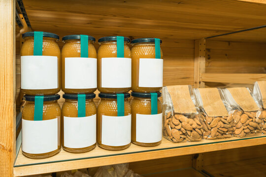 Glass jars with honey and almonds on wooden shelf