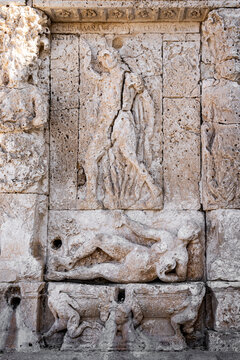 Weathered bas-reliefs and caryatids on the historic Greek Fountain in Gallipoli, a Renaissance-era monument carved in local stone, Salento, Puglia, Italy.