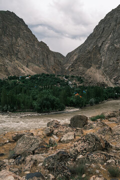 View of a river flowing through a lush valley nestled between steep, rocky mountains in Afghanistan.